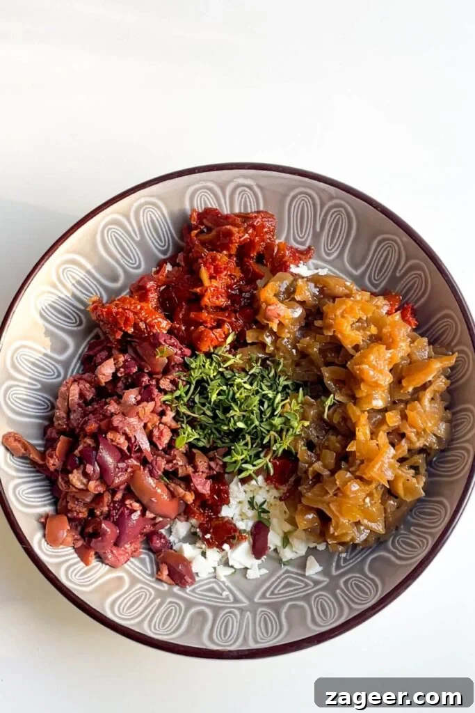 Loaded Antipasto Salami Crisps 6 Finely chopped antipasti ingredients, including olives, sundried tomatoes, and caramelized onions, in a grey bowl.