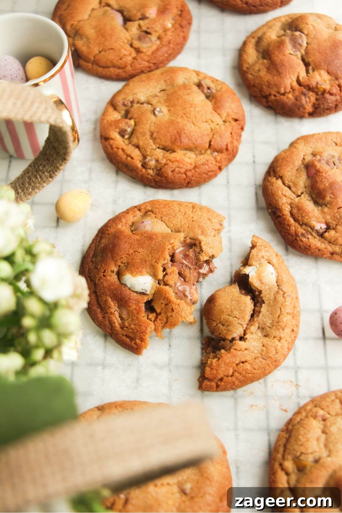 Freshly baked Mini egg cookies on baking paper, with more colorful mini eggs scattered on the side, highlighting their festive appeal.