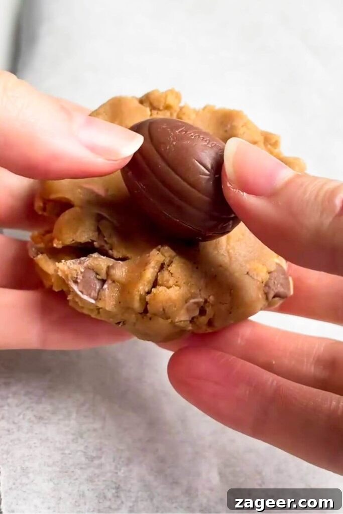 A mini Creme egg carefully placed onto a piece of flattened cookie dough.