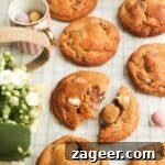 A close-up of a stack of golden brown mini egg cookies on baking paper, with a bowl of vibrant mini eggs on the side, highlighting the star ingredient.