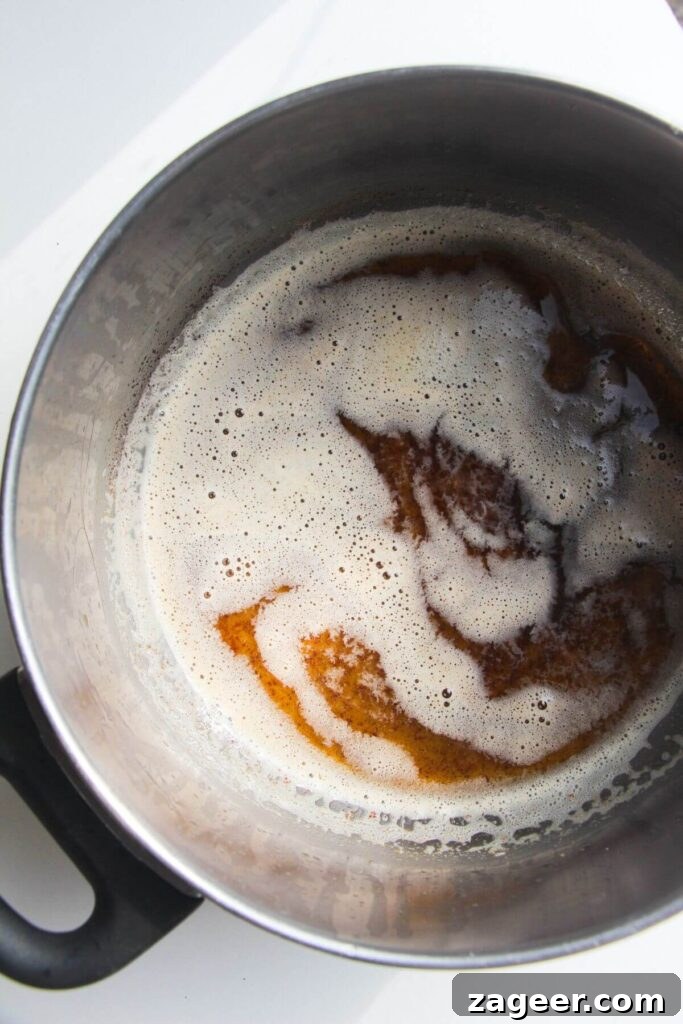 Diced butter melting and browning in a small saucepan, showing the golden-brown specks and foamy texture.