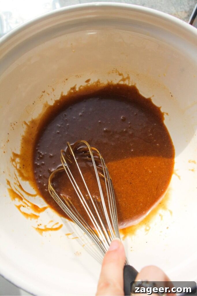 Whisking the beautifully browned butter with sugars, vanilla, miso paste, and salt in a large mixing bowl to combine the initial ingredients.