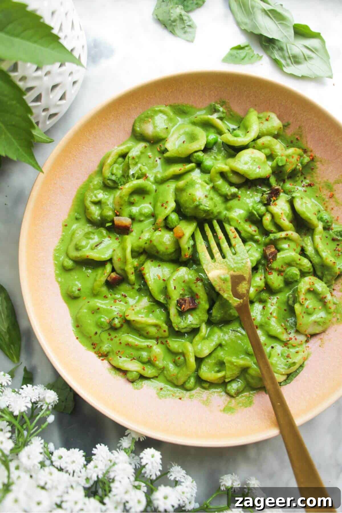 Silky Pancetta, Pea, and Spinach Pasta 2 A vibrant pink bowl filled with creamy pea, pancetta, and spinach carbonara, garnished with fresh herbs and a gold fork digging in.