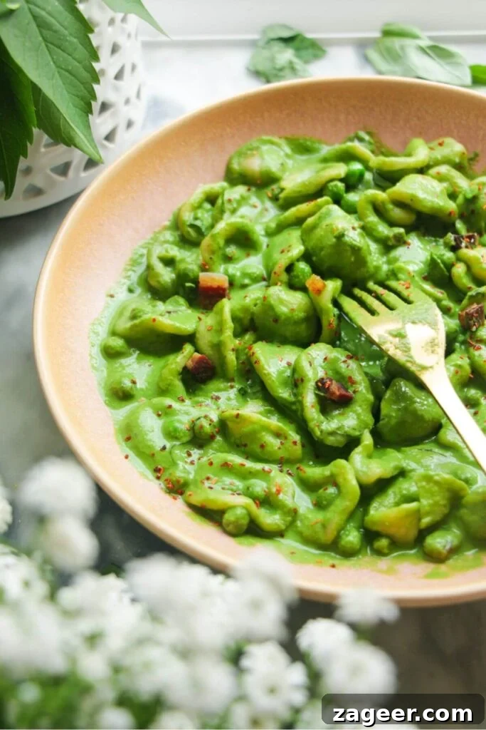 Silky Pancetta, Pea, and Spinach Pasta 11 A beautifully plated bowl of creamy pea, pancetta, and spinach carbonara, garnished with fresh herbs and a gold fork poised to enjoy.