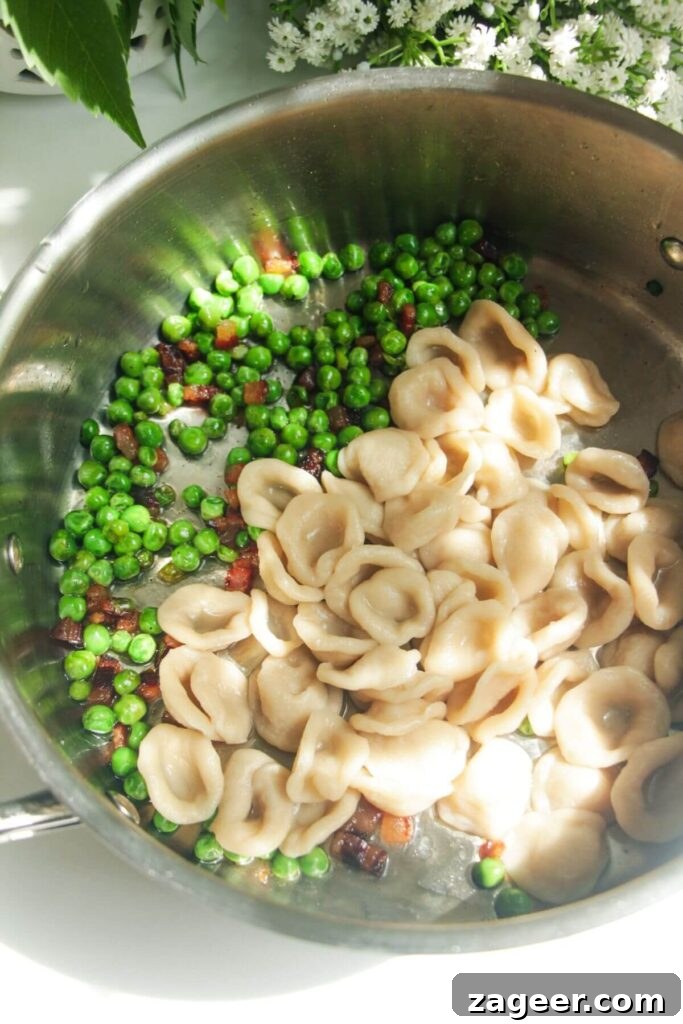 Silky Pancetta, Pea, and Spinach Pasta 7 Freshly cooked pasta being added to a pan with crispy pancetta and peas, ready to be tossed and coated.