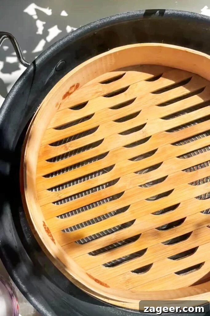 Aromatic Hot Oil Steamed Fish 5 A traditional bamboo steamer basket carefully placed inside a large metal pan, prepared for steaming.