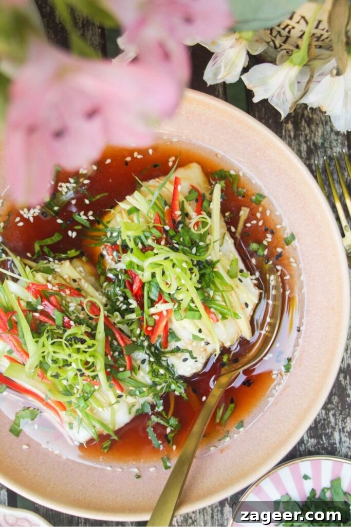 Aromatic Hot Oil Steamed Fish 10 Two perfectly steamed fish fillets, now topped with a colorful array of fresh scallions, ginger, and red chili, awaiting the hot oil drizzle in a pink bowl.