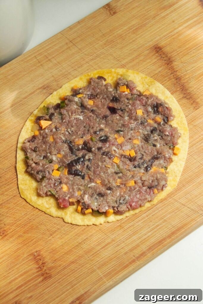 Smashed Cheeseburger Tacos 6 Cheeseburger mixture meticulously spread onto a mini tortilla, ready for pan-frying.