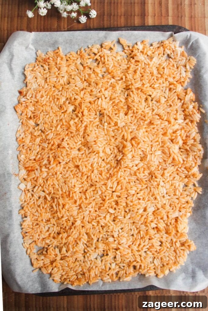 Chicken Caesar Crispy Rice Power Bowl 5 Close-up view of rice grains mixed with parmesan and paprika on an oven tray.