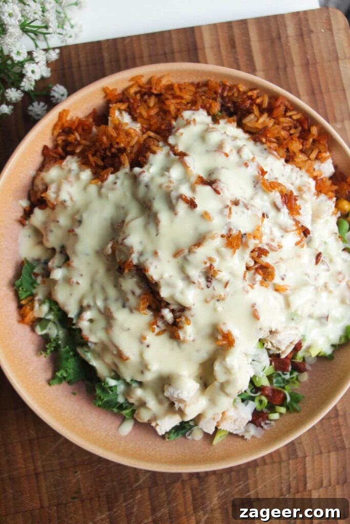 Chicken Caesar Crispy Rice Power Bowl 9 Creamy Caesar dressing being poured over the crispy rice salad in a pink bowl, ready to be tossed.