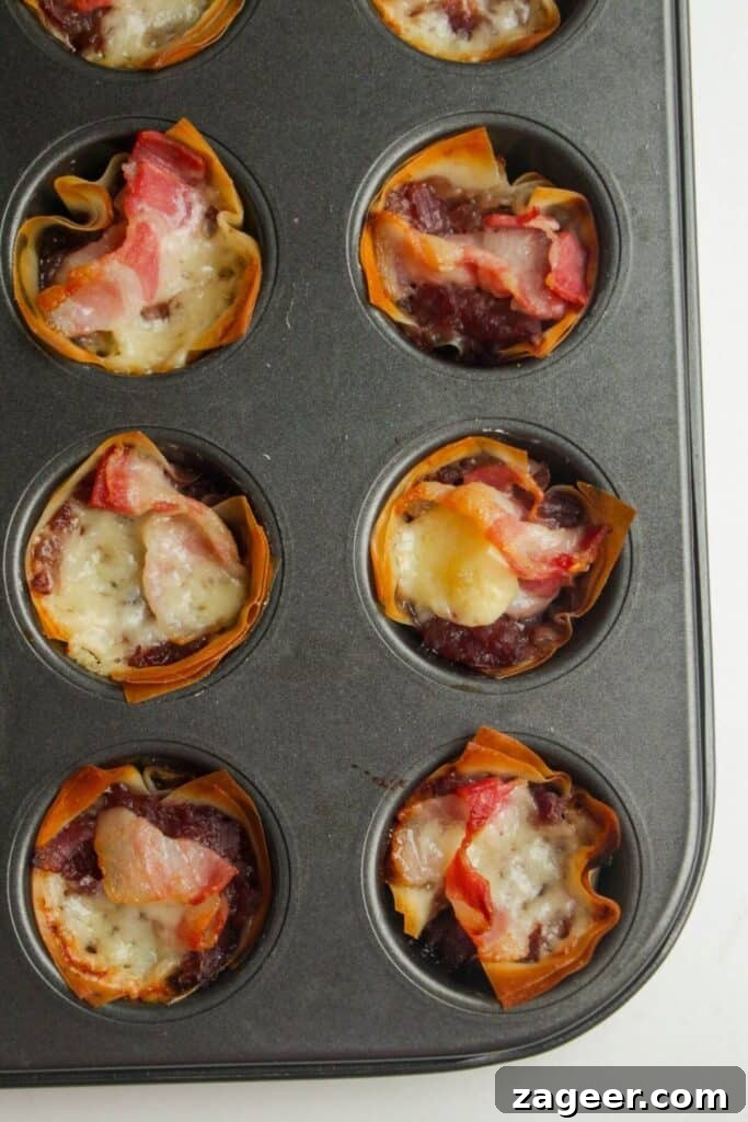 Sweet and Savory Bacon Gruyère Phyllo Tartlets 6 Close-up view of mini filo bites baking in a muffin tin, with golden edges and melted cheese.