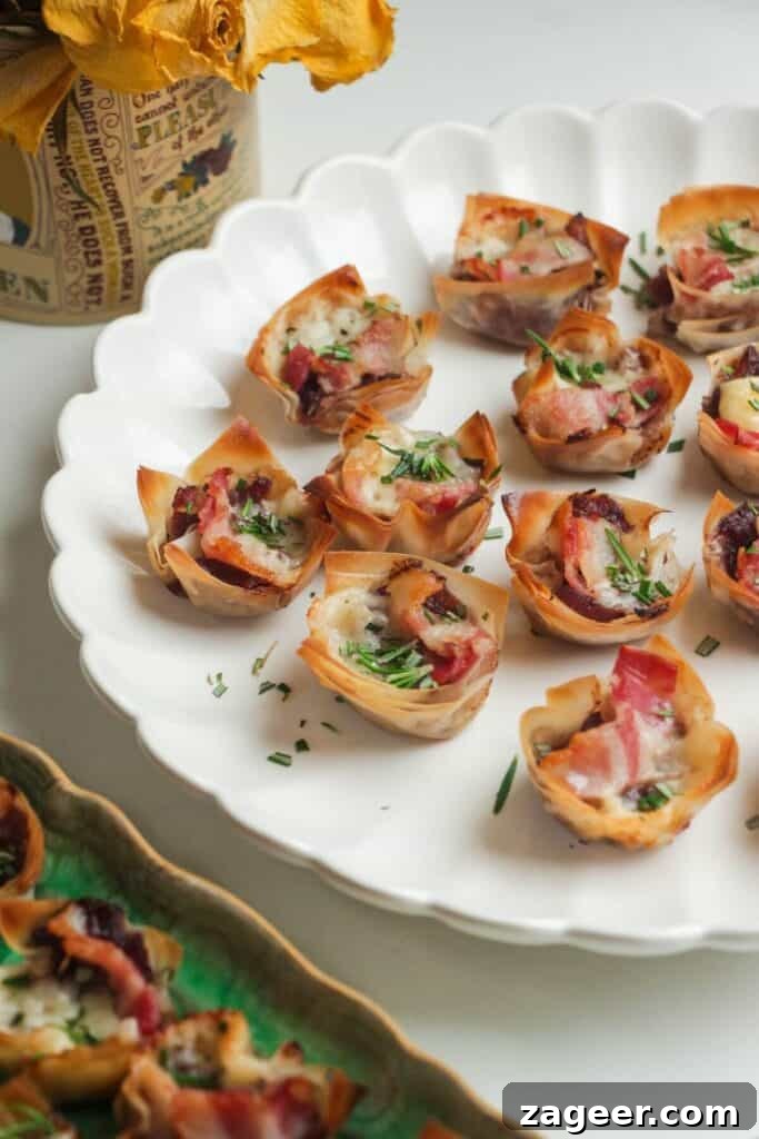 Sweet and Savory Bacon Gruyère Phyllo Tartlets 7 Baked filo bites arranged elegantly on a large scalloped serving plate.