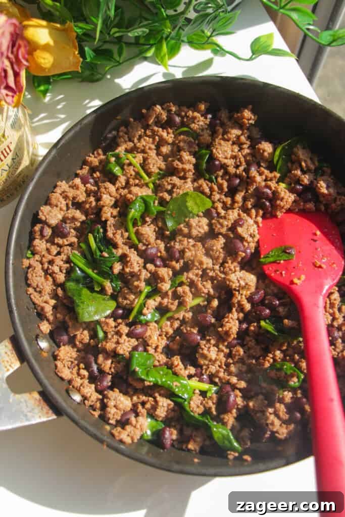 Trending Beef Power Bowls with Sweet Potato & Creamy Cottage Cheese 8 Spinach and black beans mixed through seasoned taco ground beef in a pan.