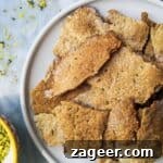Sourdough crackers on a small white plate with a little bowl of dukkah on the side.