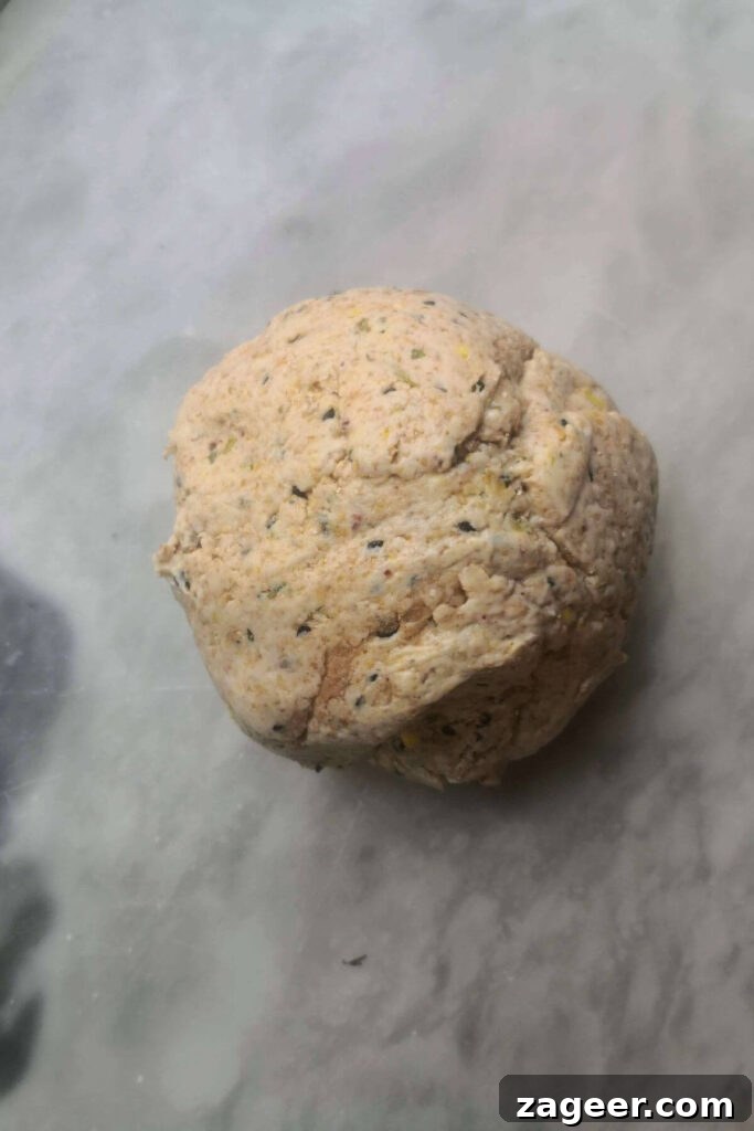 Tangy Sourdough Crisps with Aromatic Dukkah 4 Sourdough discard cracker dough, formed into a smooth ball, resting on a sleek grey marble countertop.