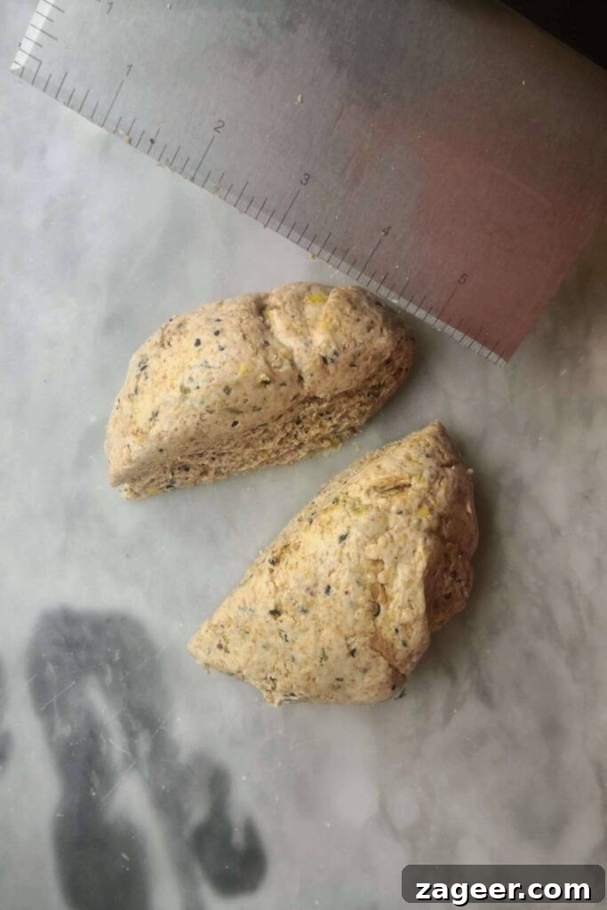 Tangy Sourdough Crisps with Aromatic Dukkah 5 Sourdough discard cracker dough being precisely cut in half with a metal dough scraper, ready for rolling.