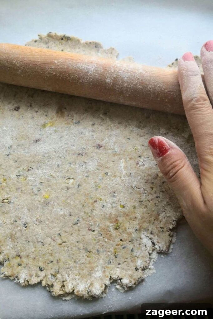 Tangy Sourdough Crisps with Aromatic Dukkah 7 A close-up view of hands diligently rolling out sourdough discard crackers with a wooden rolling pin, focusing on achieving an even, thin sheet.