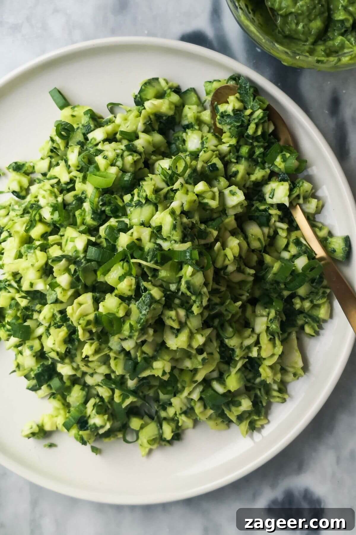 Emerald Goddess Chopped Salad Craze 2 Green goddess salad on a large white plate with a serving spoon and green goddess dressing on the side.
