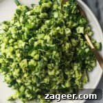 Green goddess salad on a white serving plate with a gold spoon, with green goddess dressing in a small bowl on the side.