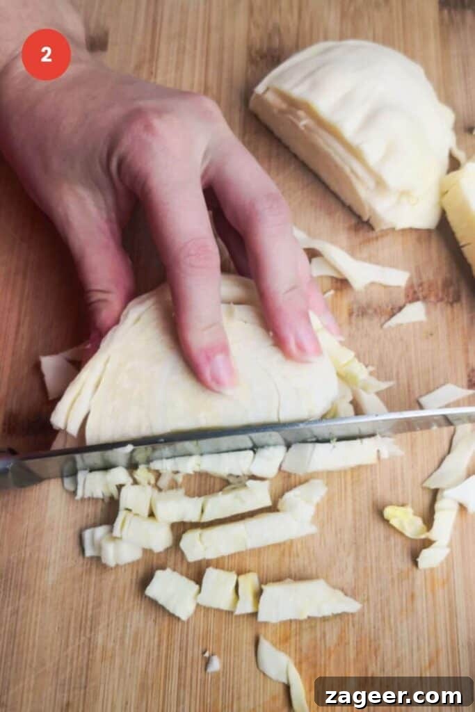 Emerald Goddess Chopped Salad Craze 6 Slicing white cabbage on a wooden board.