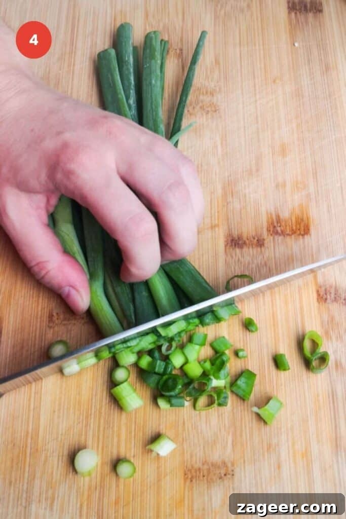Emerald Goddess Chopped Salad Craze 8 Slicing scallions with a knife on a cutting board.