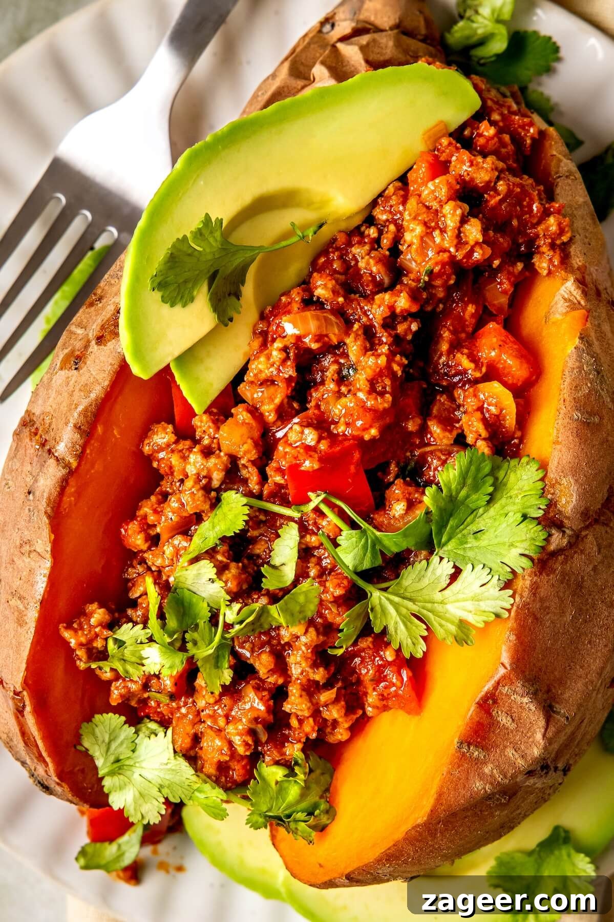 Loaded Chipotle Chorizo Sweet Potatoes 4 Two halves of Chipotle Chorizo Stuffed Sweet Potatoes artfully arranged with fresh cilantro and avocado slices.