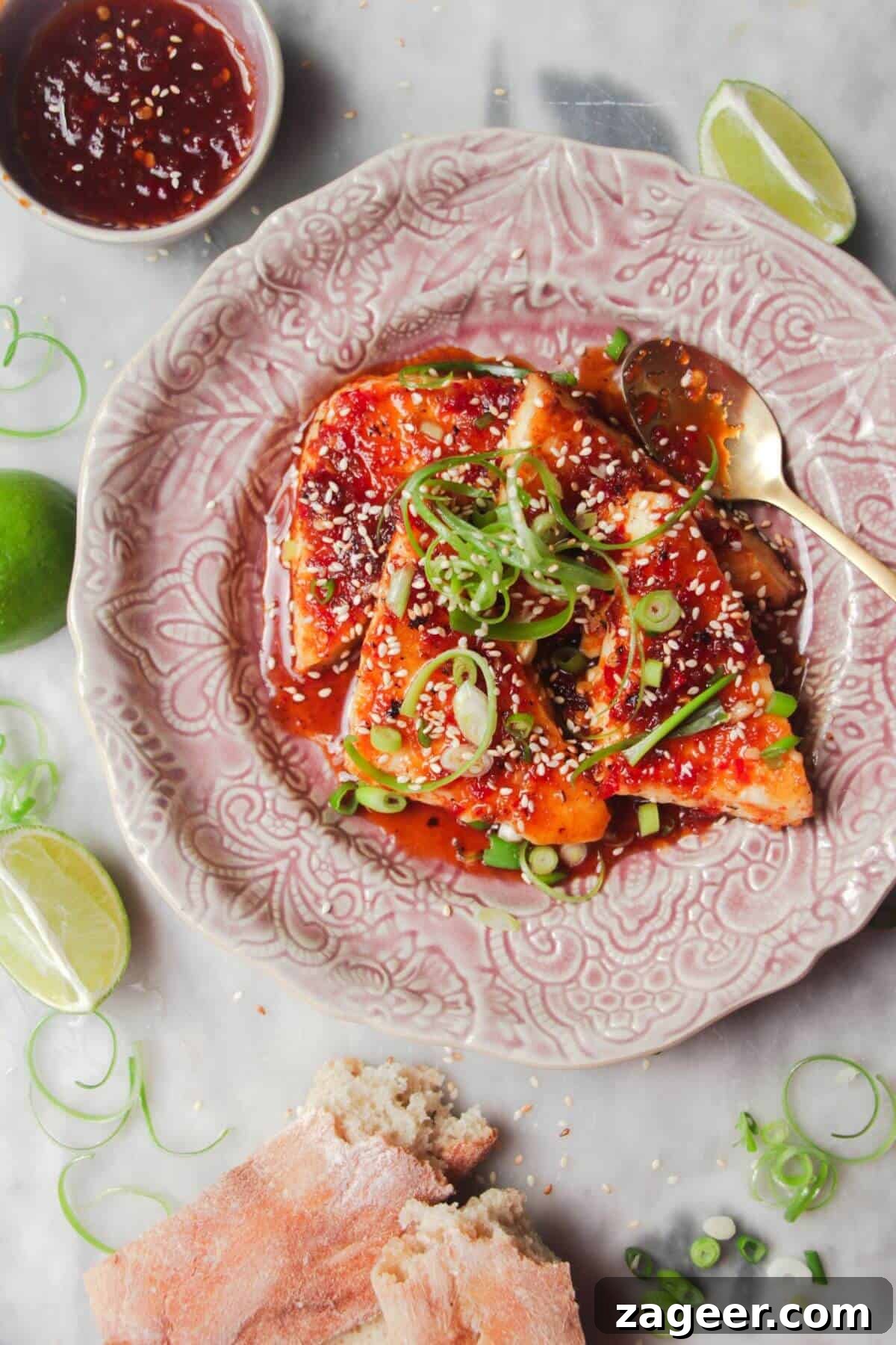 Sticky Sweet Chili Halloumi 2 Four wedges of sweet chilli haloumi on a pink plate with more sweet chilli on the side, garnished with spring onion and sesame seeds.