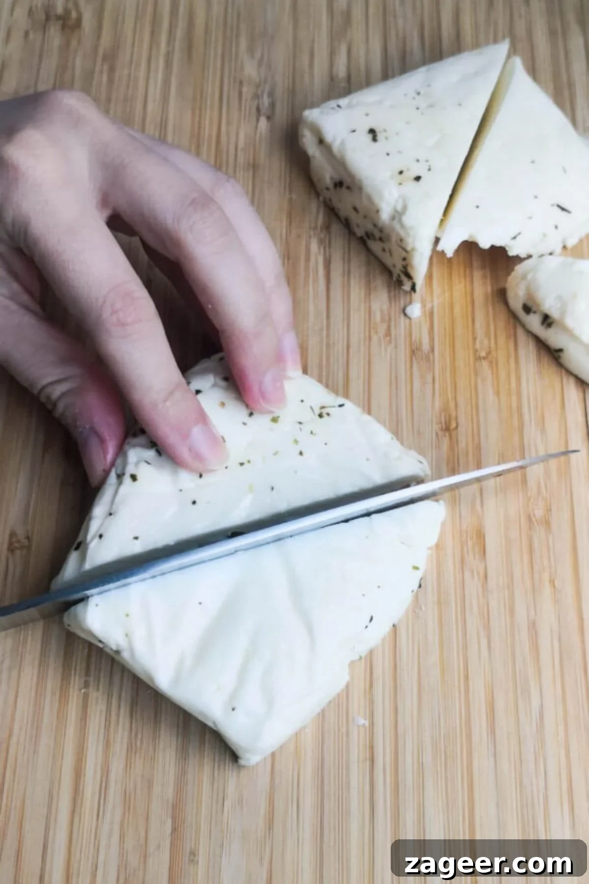 Sticky Sweet Chili Halloumi 5 Chopping halloumi into large triangles on a wooden board.