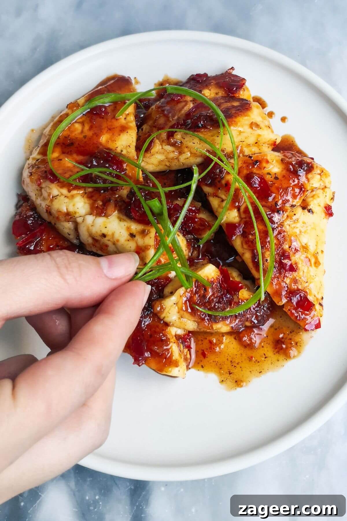Sticky Sweet Chili Halloumi 10 A hand adding curly spring onion to the top of the plate of sweet chilli halloumi.