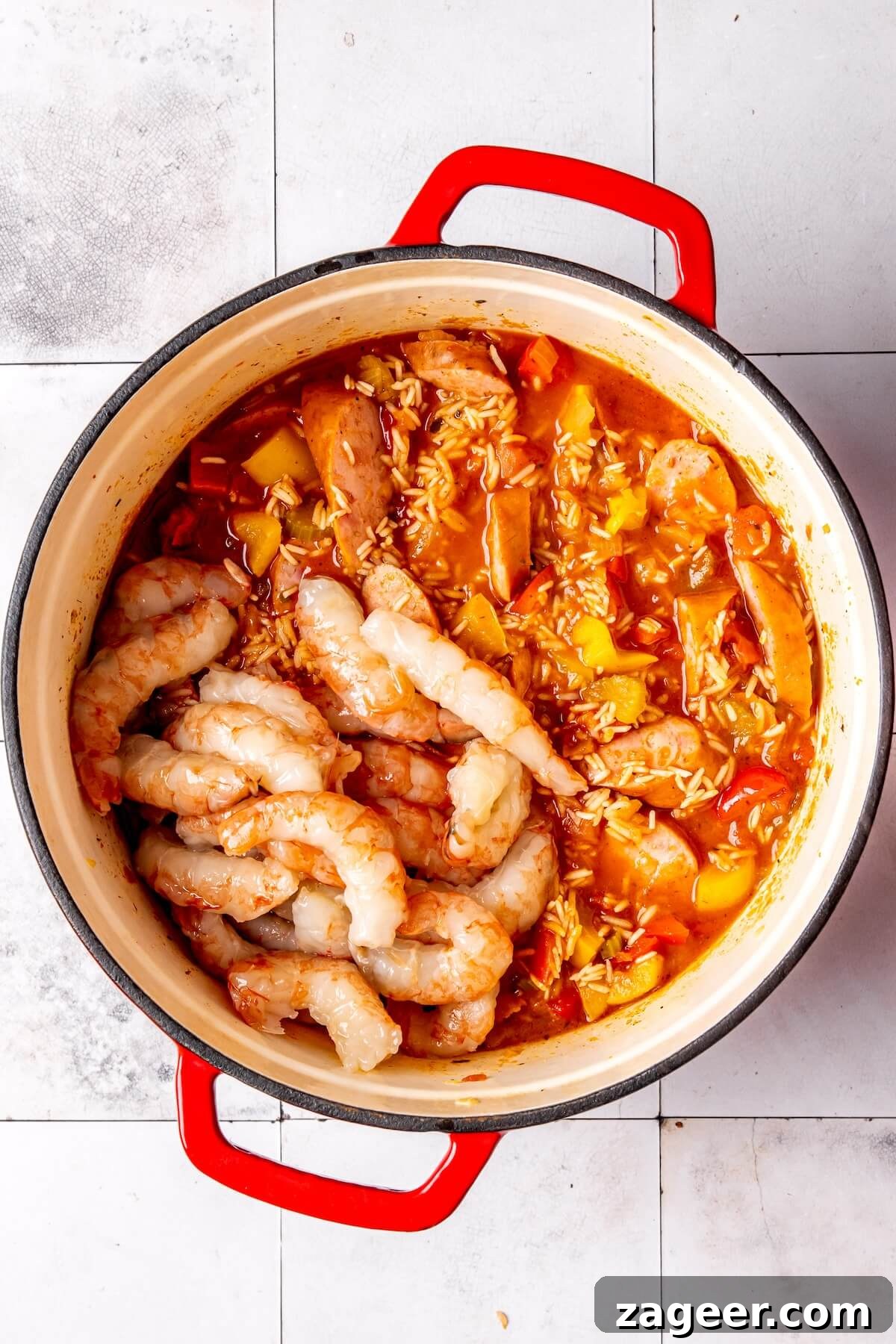 Shrimp being added and submerged into the cooking one pot Cajun rice and sausage