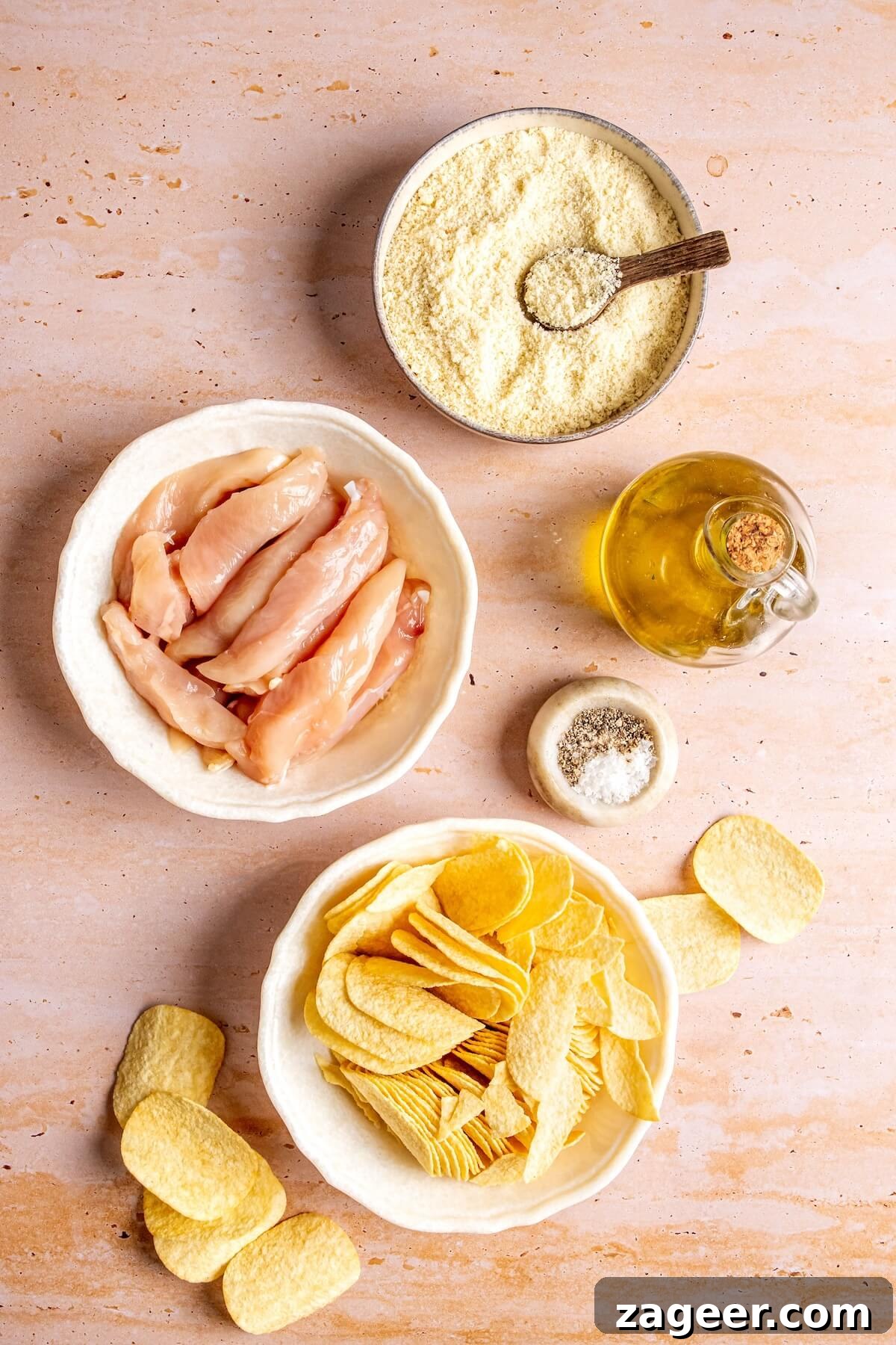 Ingredients laid out for potato chip crusted chicken tenders: chicken, chips, almond flour, olive oil, salt, pepper.