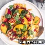 Peach and halloumi salad on a white serving plate with a small gold spoon with a jar of chilli jam in the background.