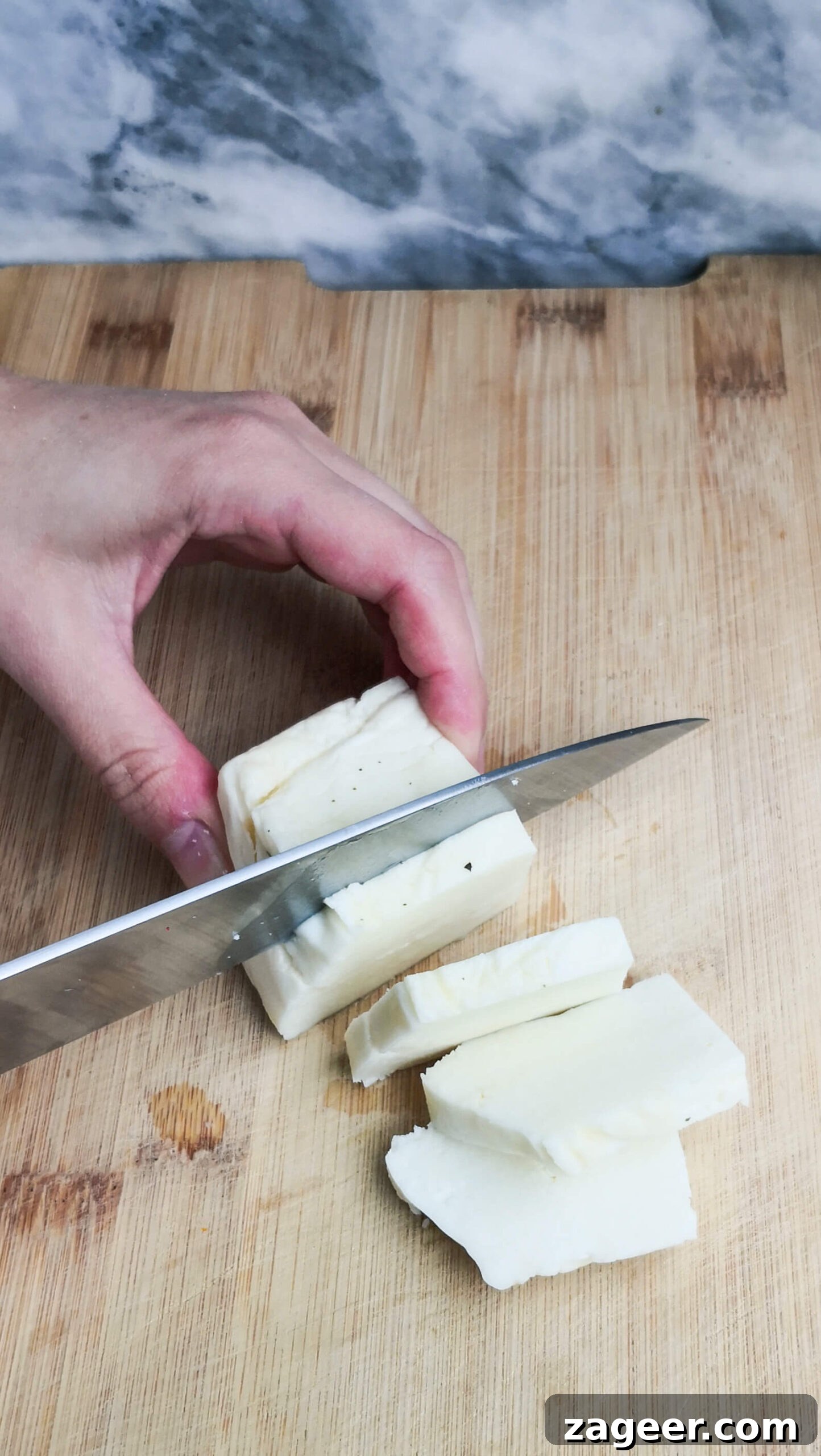 Sweet & Salty Peach Halloumi Salad with Chili Jam 4 Expertly chopping a block of halloumi into even slices on a rustic wooden cutting board, showcasing the precise preparation for the salad.