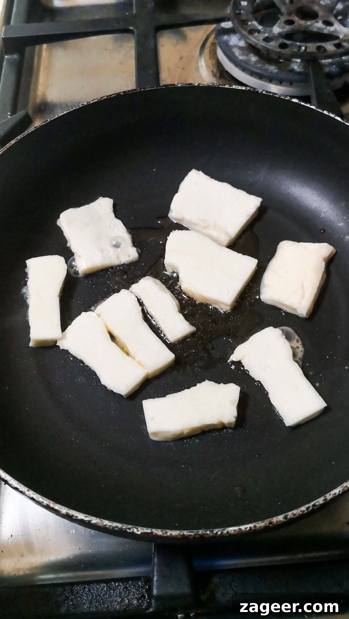 Sweet & Salty Peach Halloumi Salad with Chili Jam 6 Halloumi cooking in a small black pan, showing the initial stages of browning to achieve a golden crust for the salad.