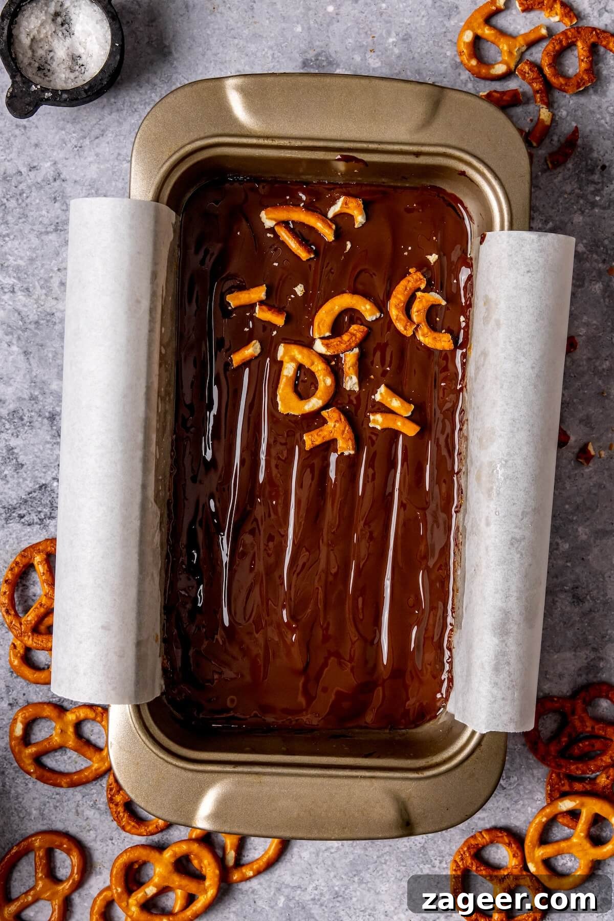 Salty Sweet No Bake Chocolate Peanut Butter Pretzel Bars 12 Final step of topping the bars with melted chocolate, crushed pretzels, and flaky sea salt.