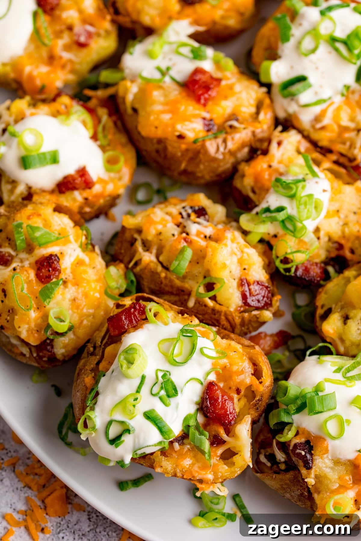 Stuffed Spud Boats 2 Loaded Potato Skins: Baked potato halves topped with melted cheese, sour cream, bacon pieces, and chopped spring onions arranged on a white plate.