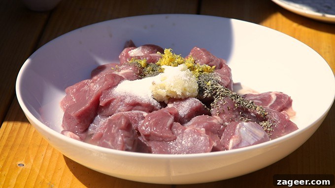 Tender Greek Lamb Souvlaki Skewers 2 Chunks of lean lamb being mixed with a vibrant marinade of garlic, lemon, and dried herbs in a bowl.