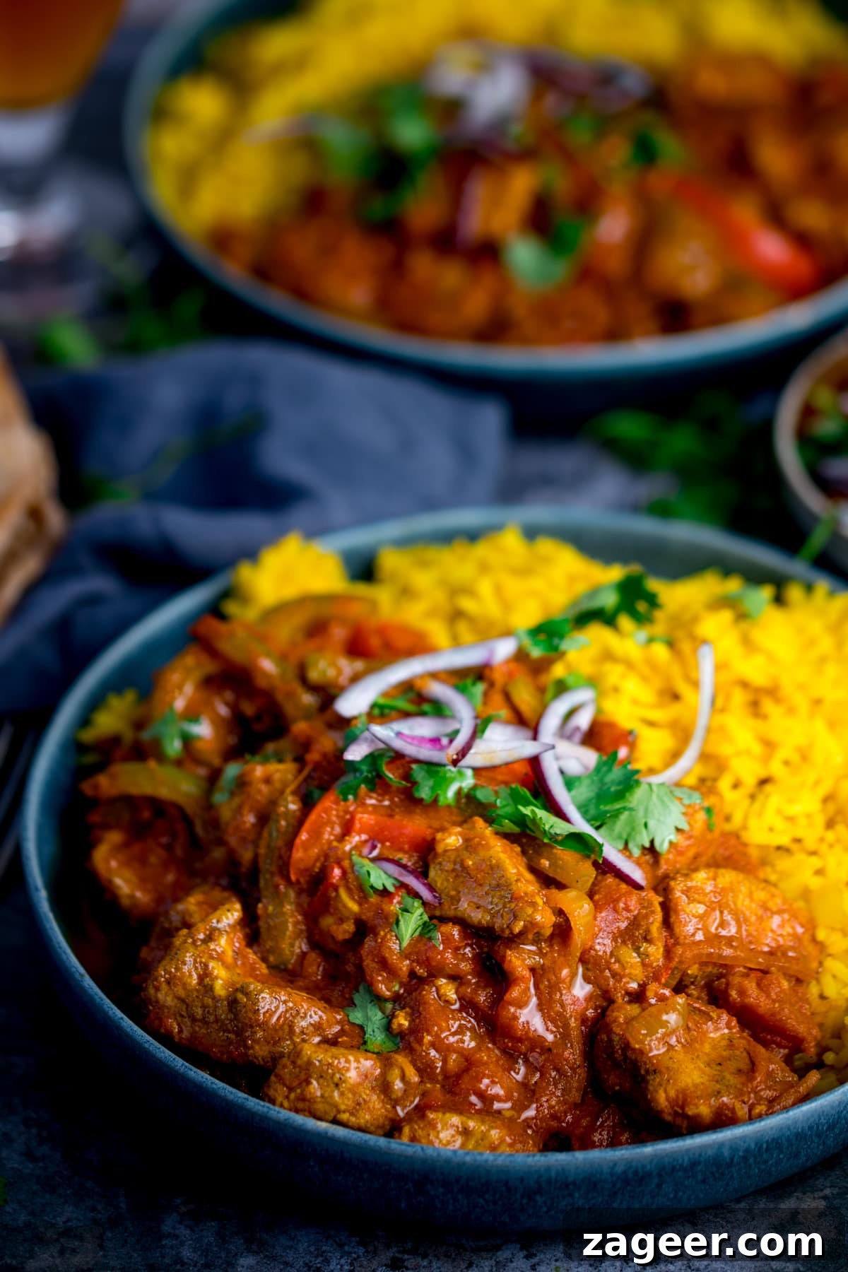 Vibrant Spicy Chicken Jalfrezi 2 Spicy Chicken Jalfrezi with fragrant pilau rice, garnished with fresh red onion and coriander for a vibrant presentation.