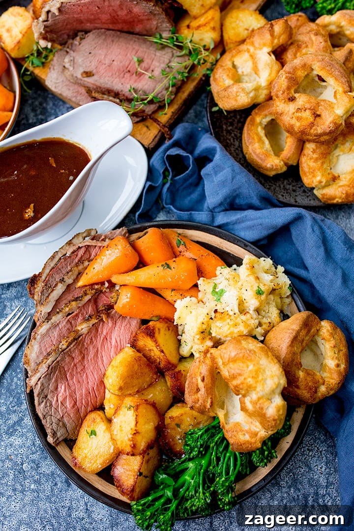 Perfect Roast Beef Every Time: Your Planning Blueprint 2 Overhead image of a beautifully prepared roast beef dinner with all its trimmings: roast beef, Yorkshire puddings, crispy roast potatoes, gravy, carrots, broccoli, and cauliflower cheese.
