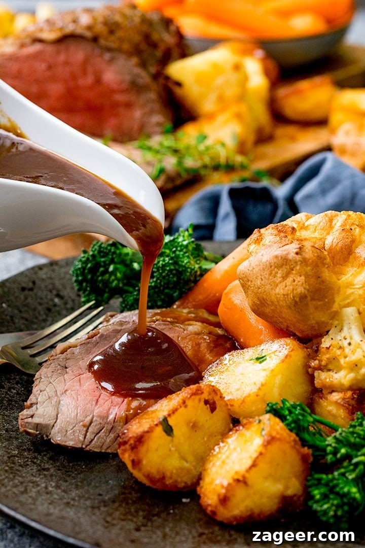 Perfect Roast Beef Every Time: Your Planning Blueprint 5 A close-up shot of rich beef gravy being poured generously over a plate of roast beef, crispy roast potatoes, and a Yorkshire pudding.
