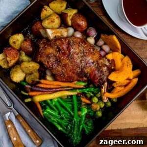 roast lamb shoulder and vegetables in a roasting tin with jug of gravy