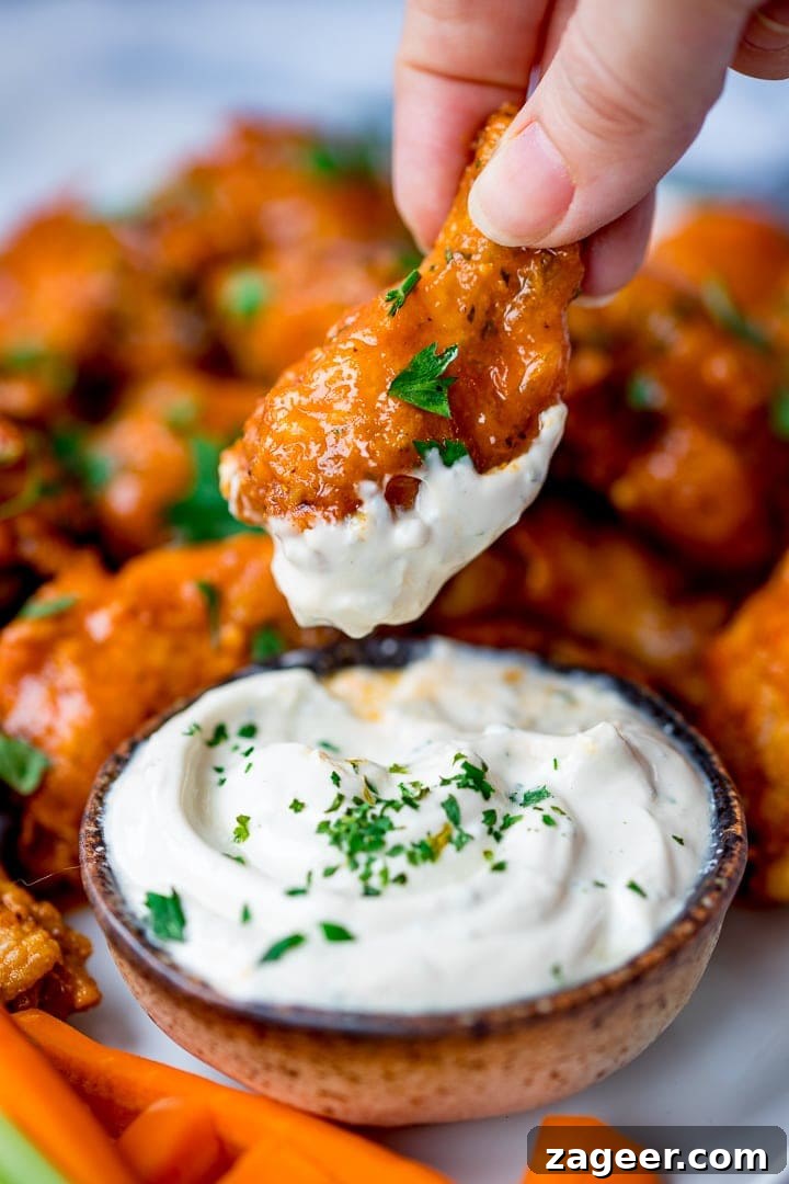 Golden Crisp Oven Buffalo Wings 7 Buffalo chicken wing being dipped in blue cheese sauce