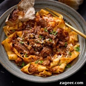 Hearty beef ragu generously tossed with wide pappardelle pasta, served in an attractive green bowl, inviting diners to enjoy a classic Italian comfort meal.