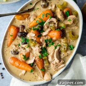 White oblong serving bowl filled with a hearty and steaming chicken casserole, garnished with fresh herbs, ready to be enjoyed.