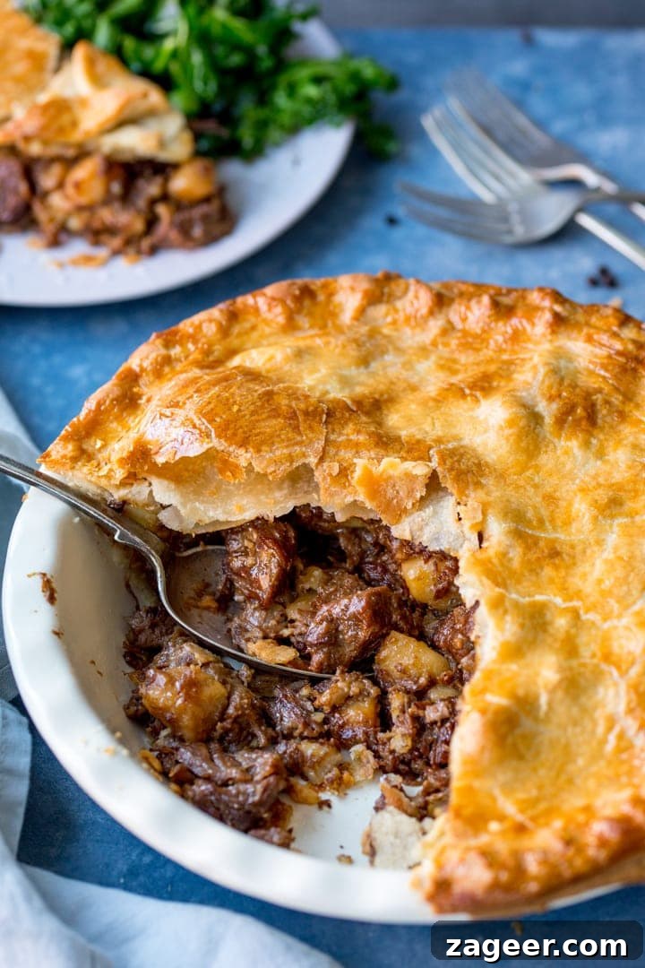 Melt-in-Your-Mouth Slow-Cooked Steak Pie 2 Large steak and potato pie with slice taken out, showcasing the rich, slow-cooked filling.
