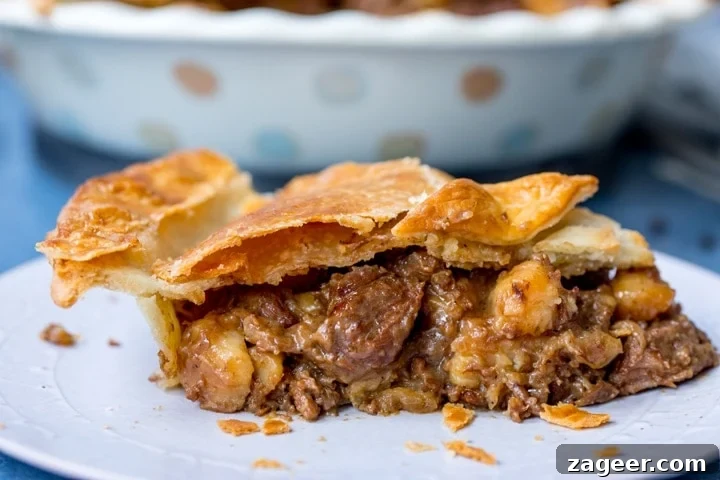 Melt-in-Your-Mouth Slow-Cooked Steak Pie 11 Wide image of a delicious slice of steak and potato pie on a plate, showing the tender beef and potatoes within.