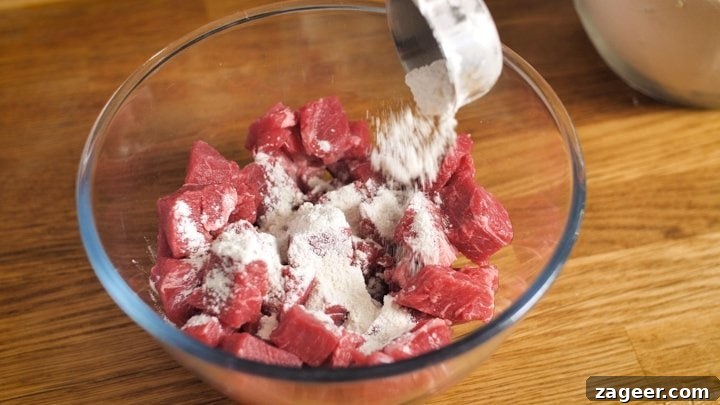 Melt-in-Your-Mouth Slow-Cooked Steak Pie 4 Cubes of beef being coated in seasoned flour, a crucial step for thickening and flavour.
