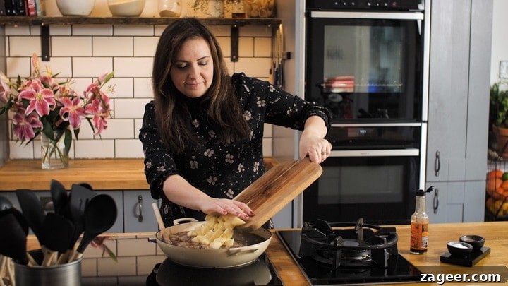 Melt-in-Your-Mouth Slow-Cooked Steak Pie 5 Nicky Corbishley adding chopped potatoes to the rich beef mixture in a pan.
