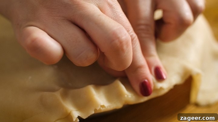 Melt-in-Your-Mouth Slow-Cooked Steak Pie 8 Fingers crimping the pastry edge to create a beautiful, decorative crust.