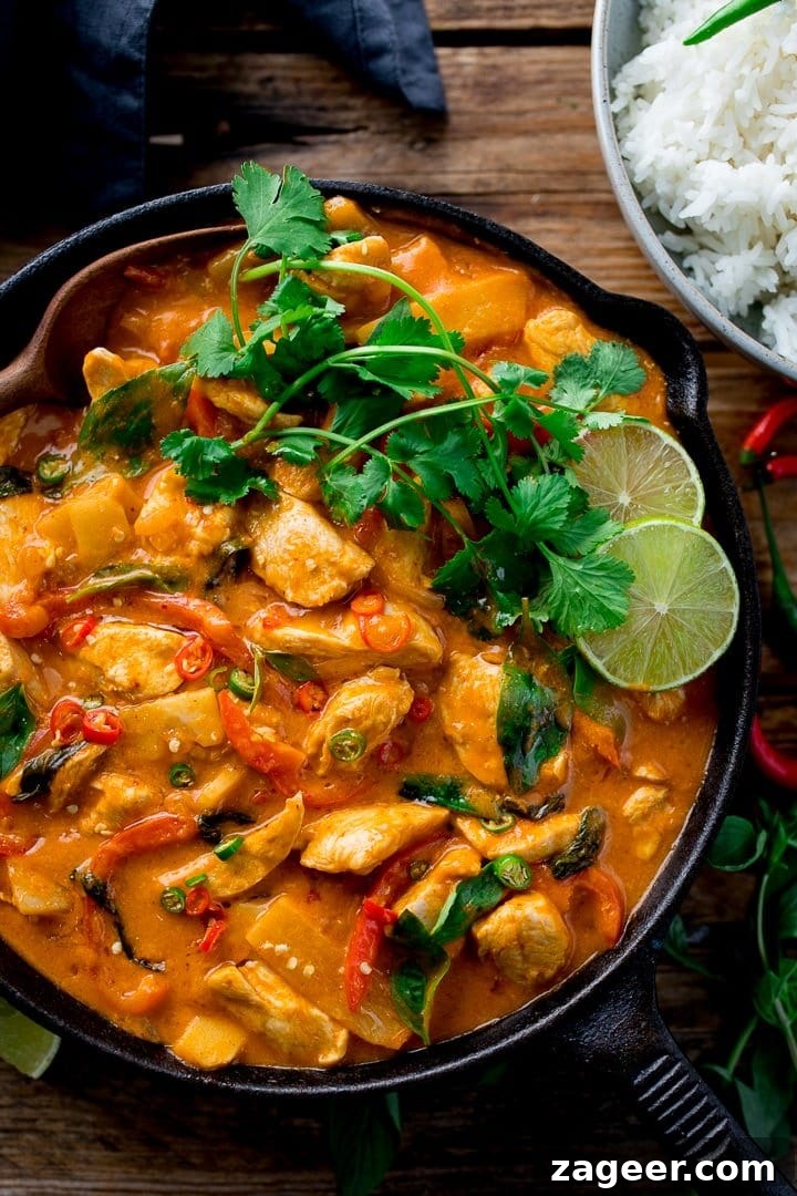 Vibrant Thai Red Chicken Curry 6 Thai red chicken curry simmering in a large, shallow pan, showing rich red sauce, tender chicken, and vibrant green basil leaves.